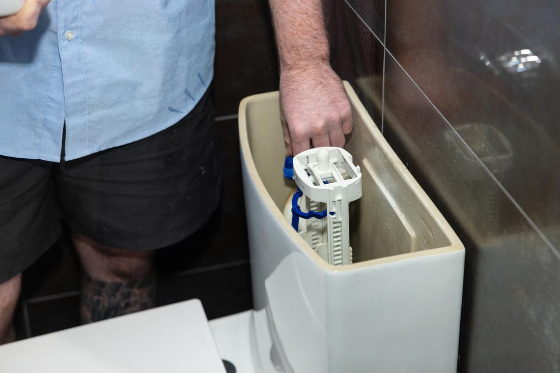 Projection plumber repairing a toilet cistern